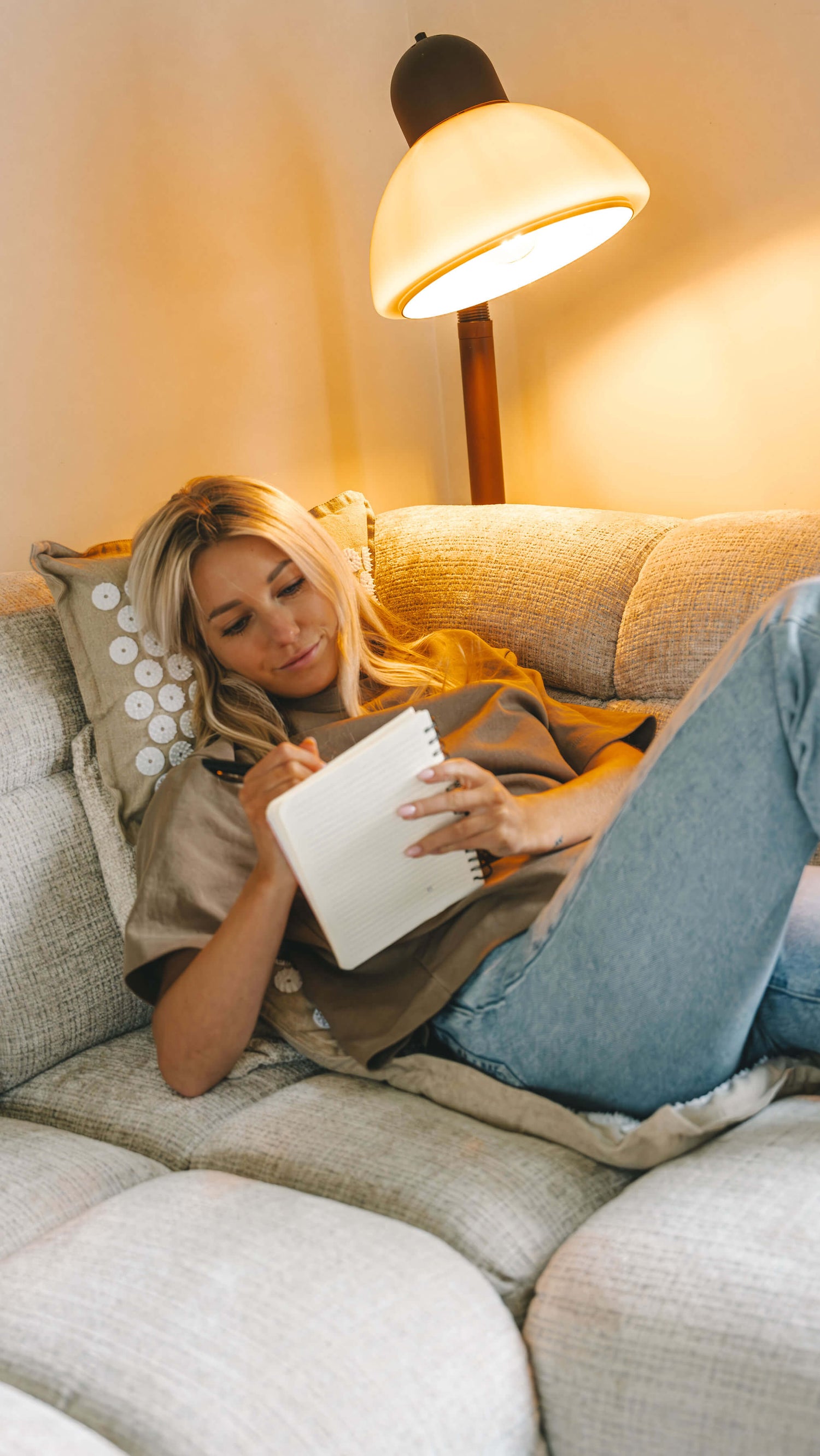 Anne van de Kerkhof ontspant op de bank op de Calmness Eco Spijkerset terwijl ze aan het journalen is