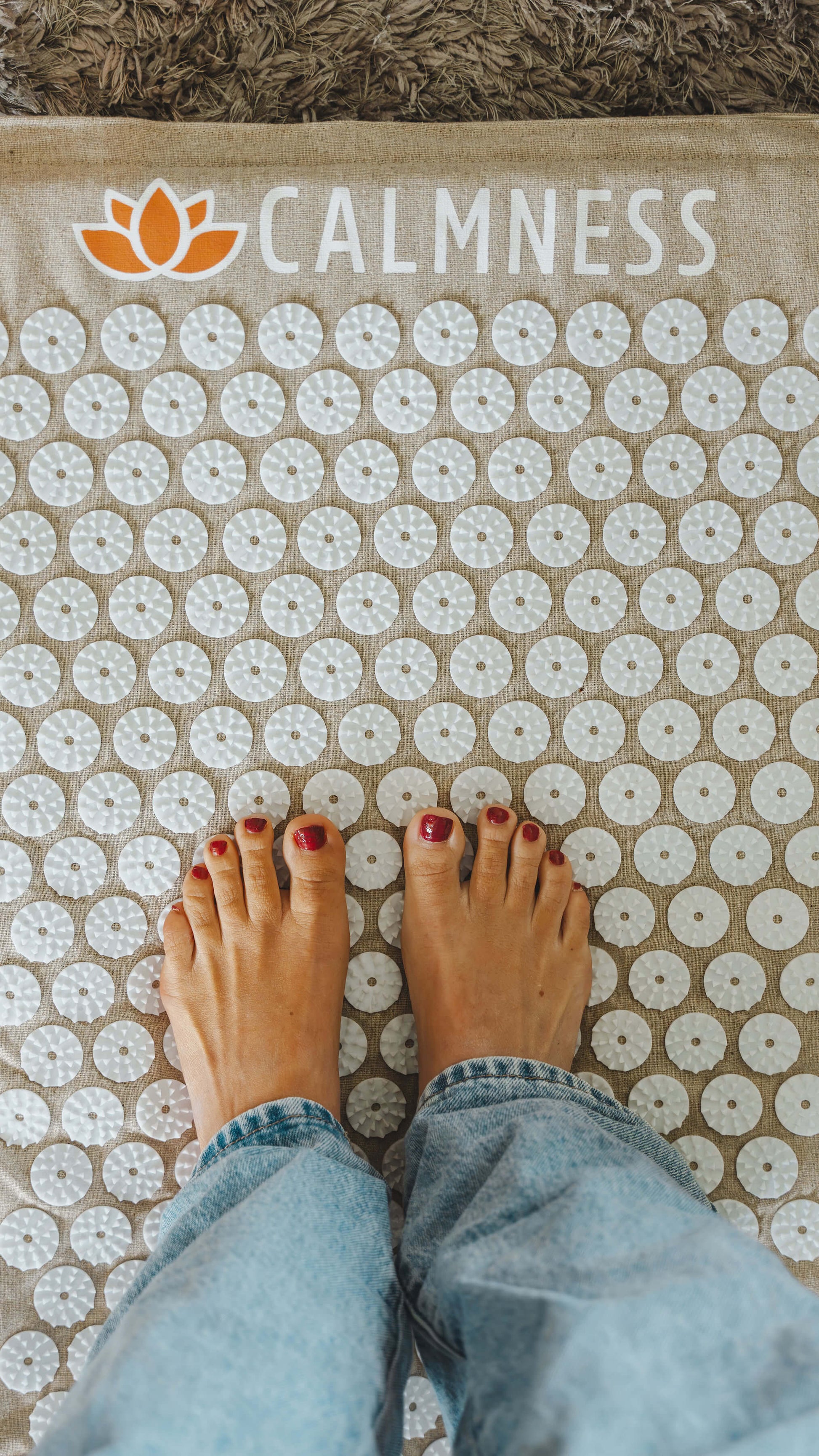 Anne van de Kerkhof standing on the Calmness Eco Acupressure Mat to relax her feet and improve blood circulation